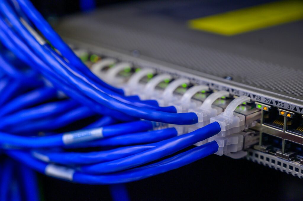 Detaljeret visning af blå Ethernet-kabler forbundet til en netværksswitch i et datacenter.